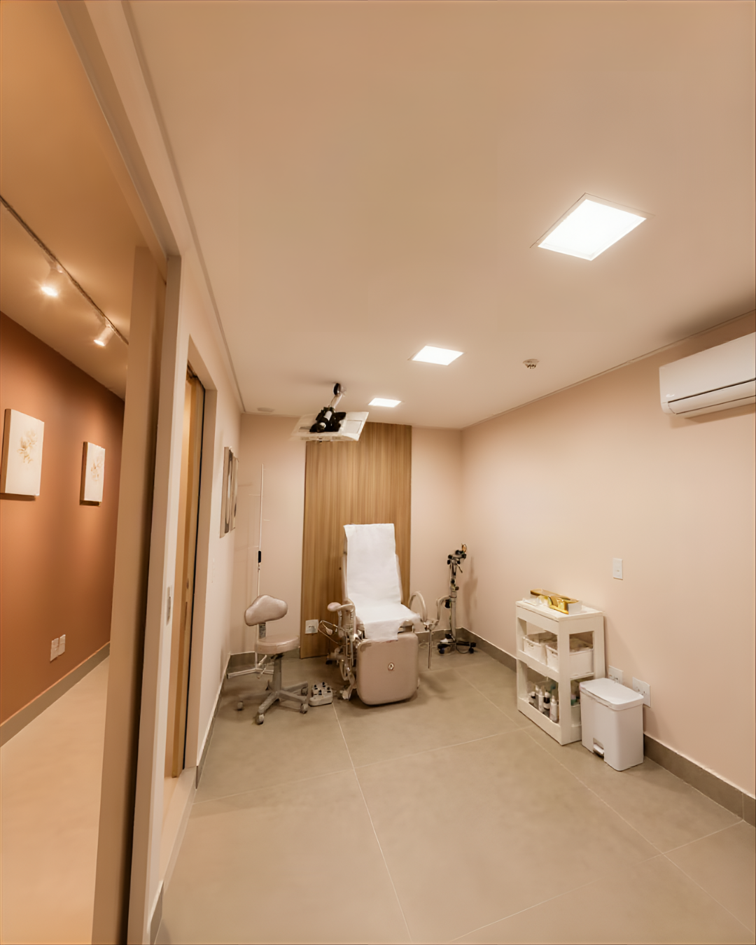 Consultório ginecológico com maca de exame e iluminação acolhedora